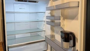 An open refrigerator with multiple shelves and a coffee maker on the door shelf.