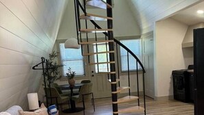 A loft-style living area with a staircase, a sofa, a coffee table, and a dining area.