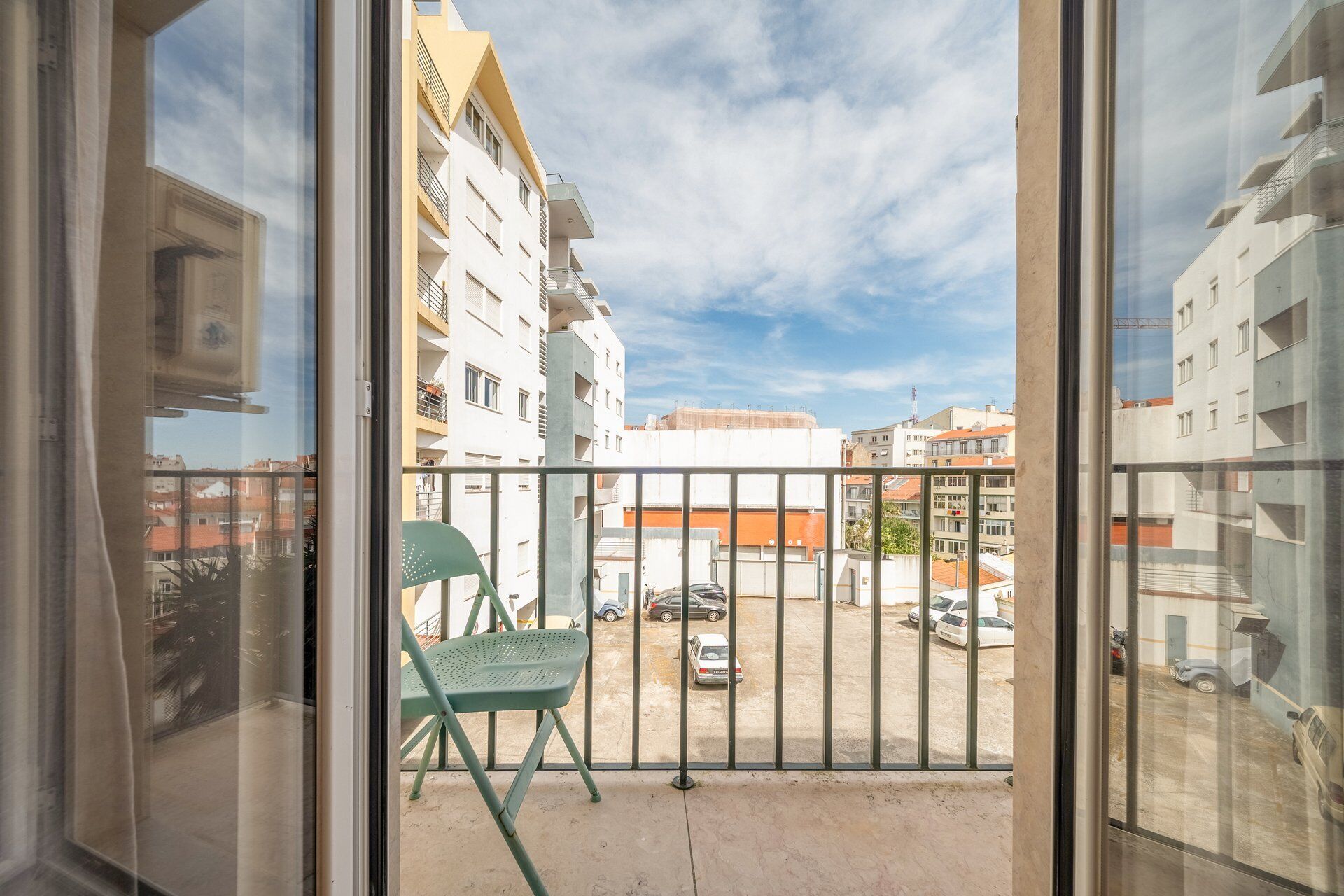 A balcony with a view of a parking area and buildings.