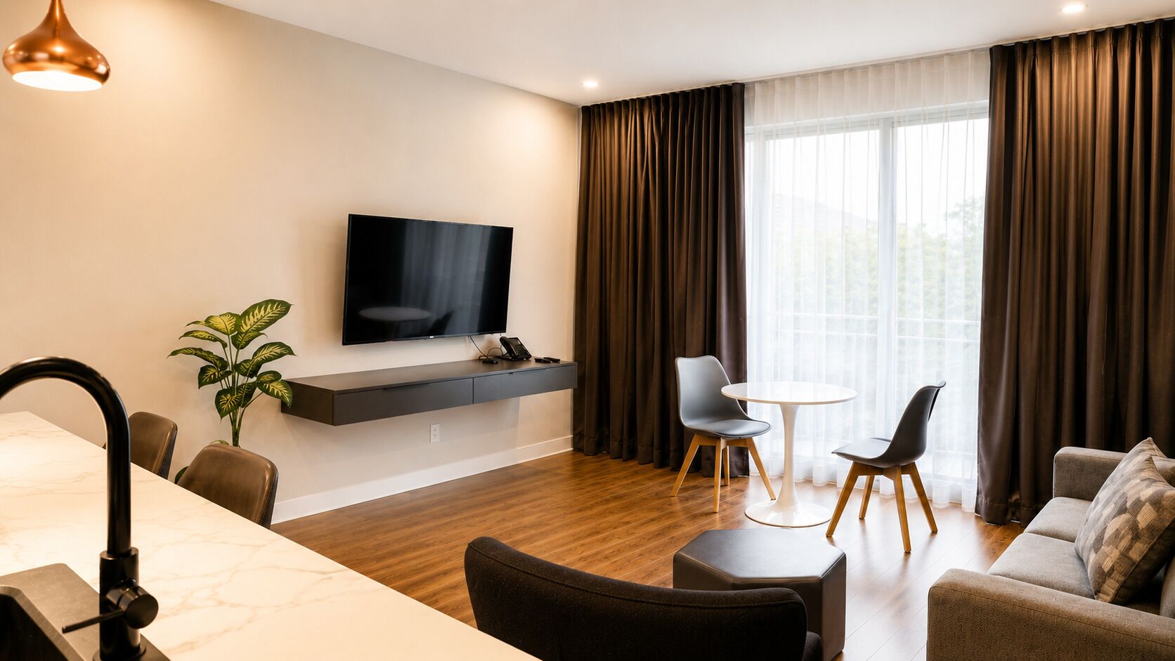 A modern living room with a flat-screen TV, a dining area with a table and chairs, and a sofa.