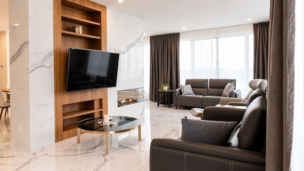 A modern living room with a flat-screen TV, a glass-top coffee table, a sofa, and a fireplace. - Loft 1325 (Val-d'Or)