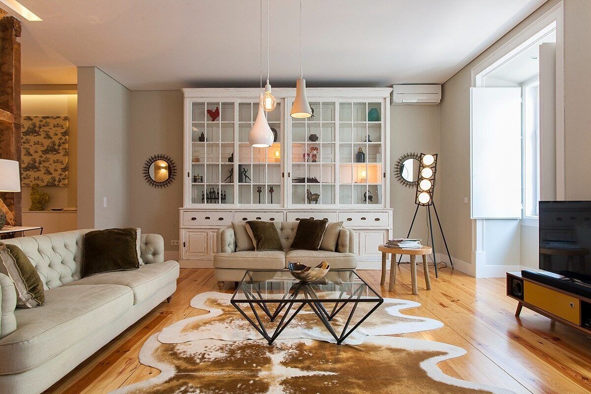Een woonkamer met een bank, een glazen salontafel, een kast met glazen deuren en een televisie.