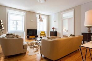 Een woonkamer met een bank, fauteuil, televisie en decoratieve accessoires.