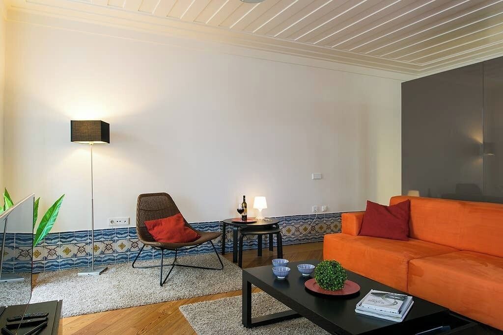 A modern living room with a sofa, a chair, a coffee table, a floor lamp, and a small table with a lamp.