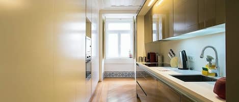 A modern kitchen with wooden flooring, a central island, and a window providing natural light.