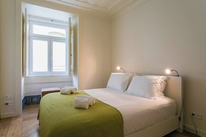 Ein Schlafzimmer mit einem Bett, einem Fenster und einer Nachttischlampe.