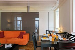 Ein modernes Wohnzimmer mit einer Couch, einem Esstisch mit Frühstück und einem großen Fenster.