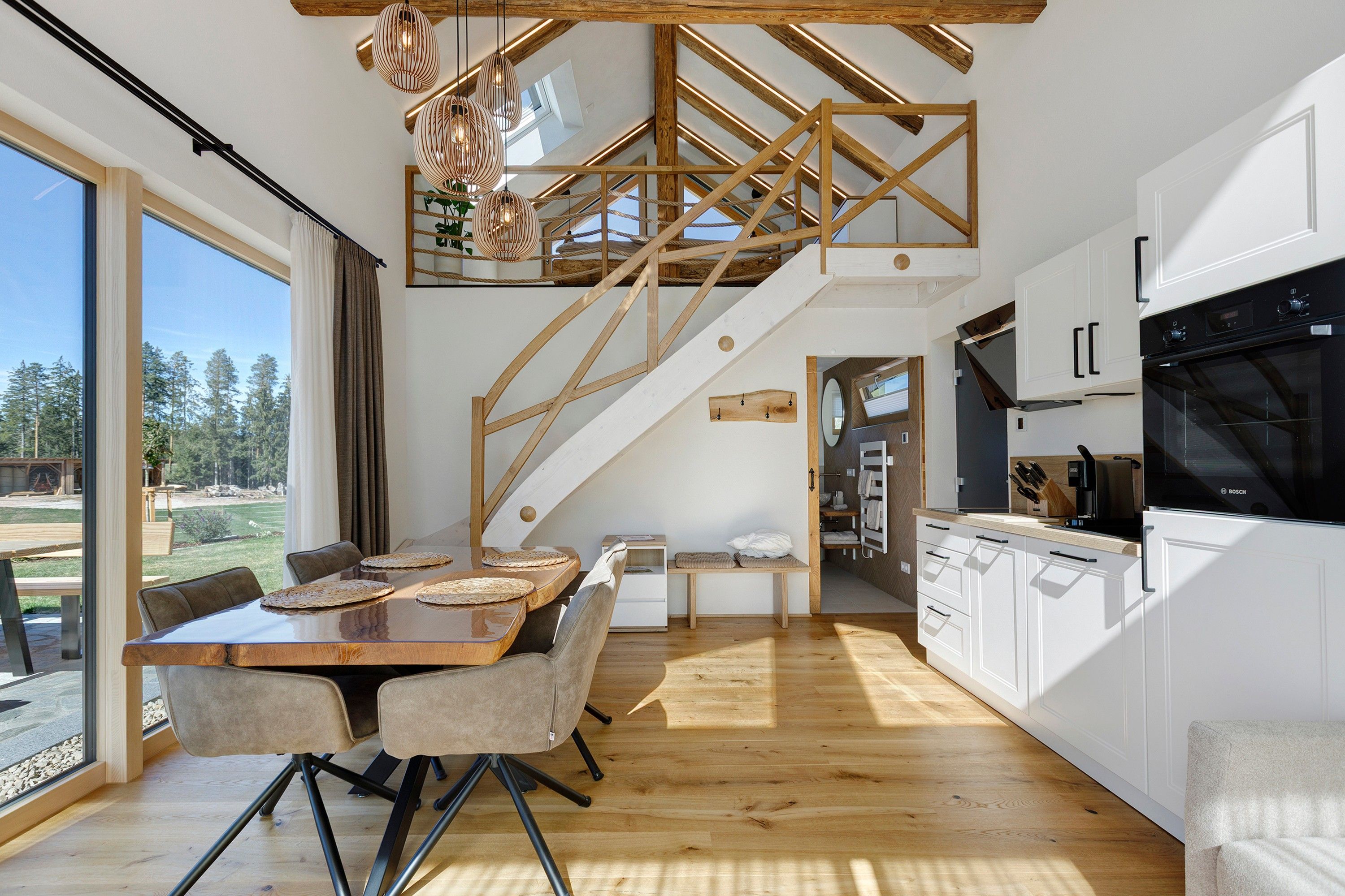 A modern kitchen with white cabinets, a Bosch oven, and a dining area with a wooden table and chairs.
