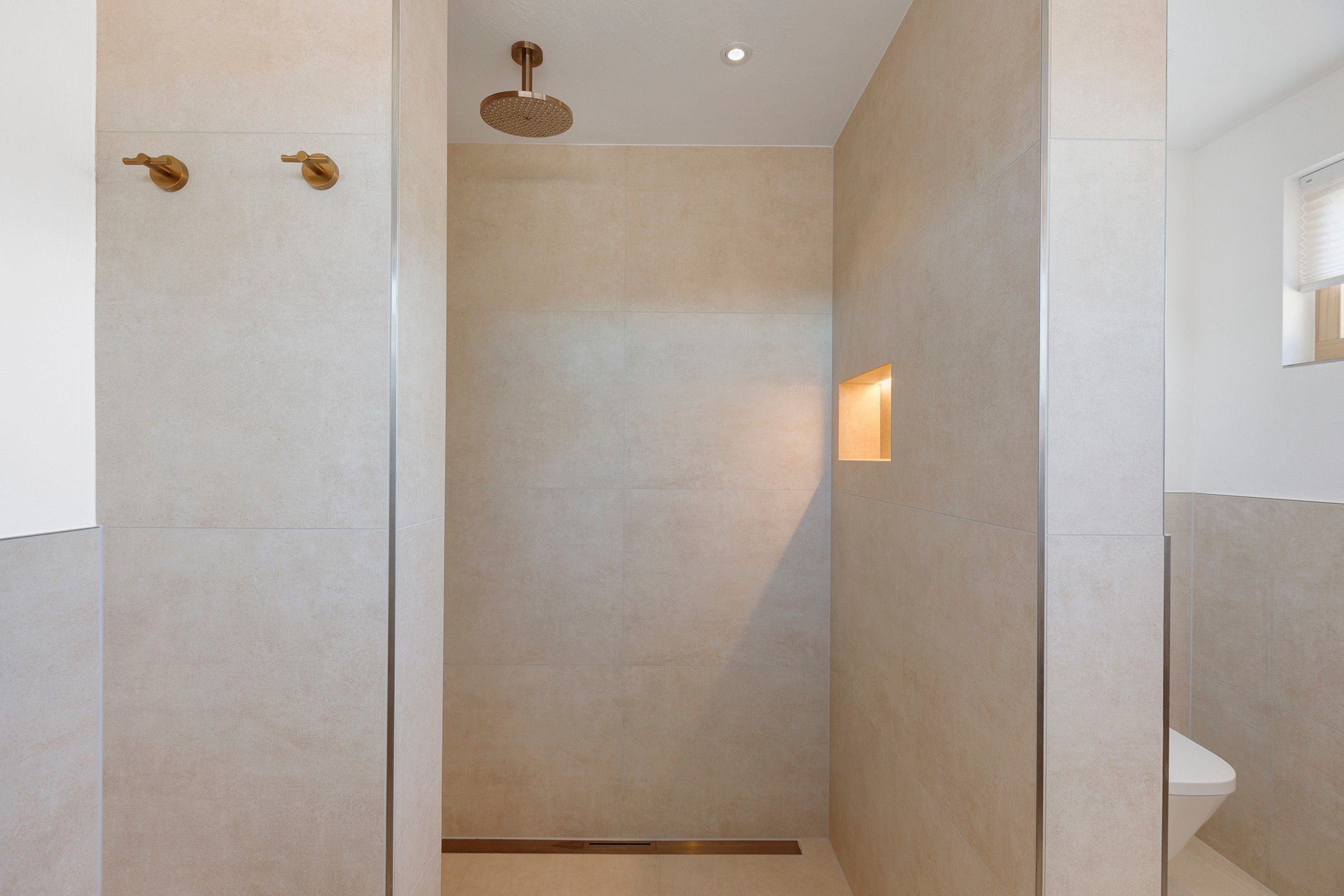Ein modernes Badezimmer mit Dusche, Wandleuchte und Deckenlampe.