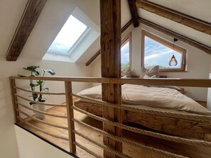A loft bedroom with a wooden bunk bed, a skylight, and a view of the outdoors.
