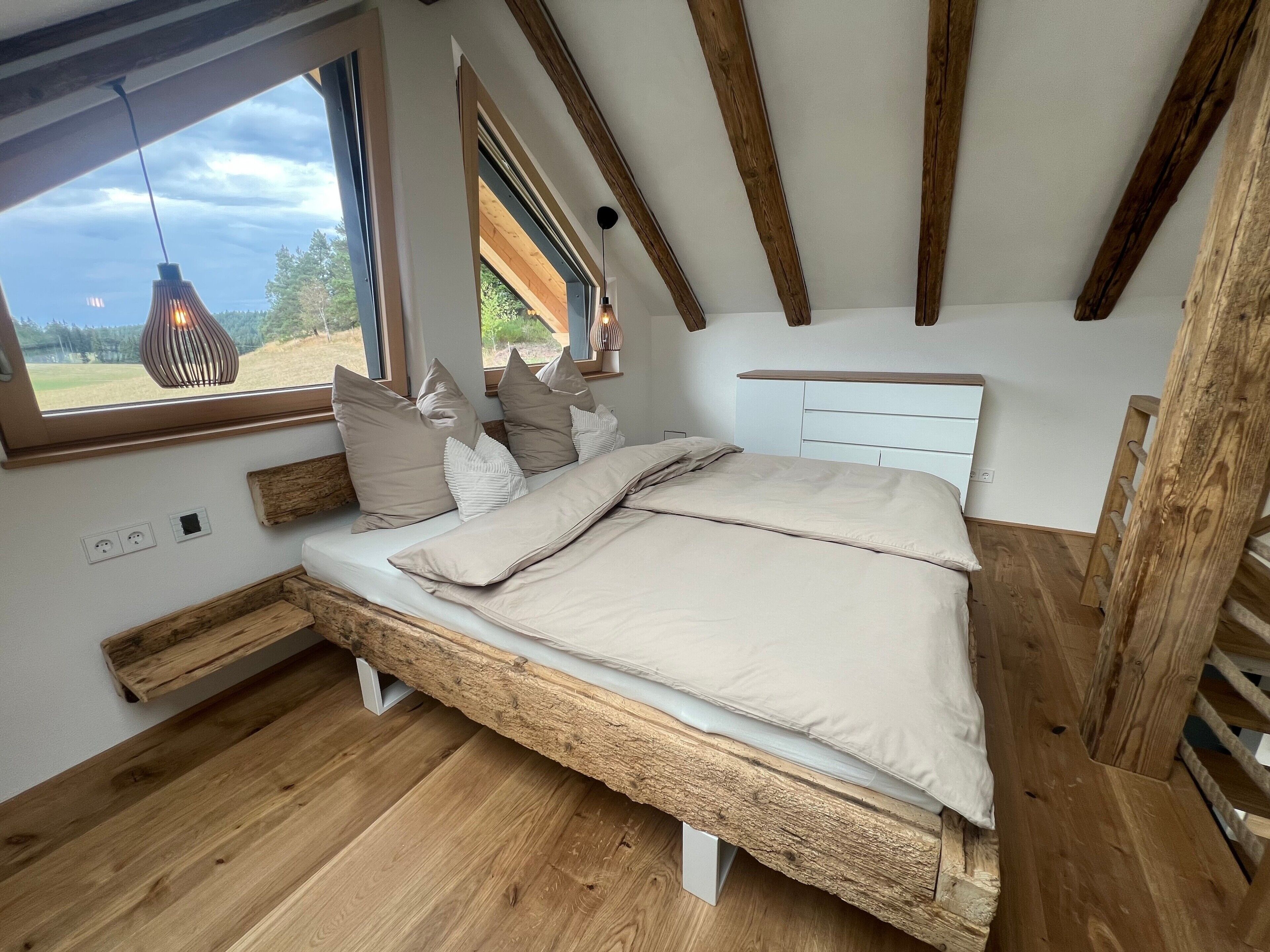 Ein Schlafzimmer mit einem hölzernen Bett, einem Fenster mit Blick und einer Hängeleuchte.