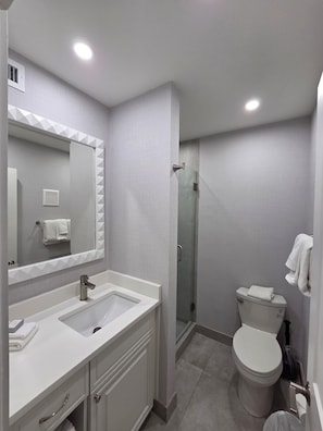 A modern bathroom with a double sink, a toilet, and a shower enclosure. - High Point World Resort  (Kissimmee)