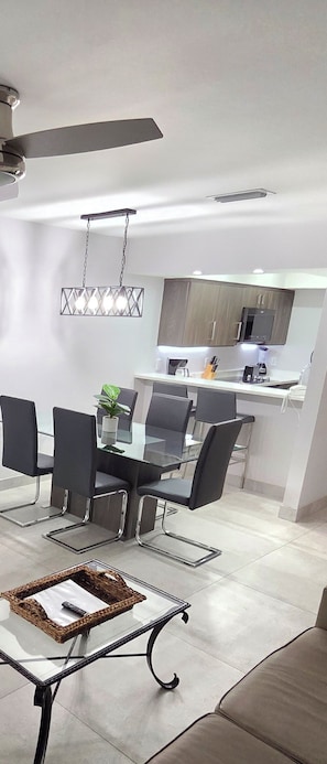 A modern kitchen with a dining area, a ceiling fan, and a hanging light fixture. - High Point World Resort  (Kissimmee)