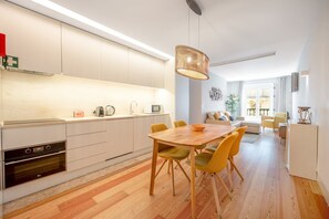 A modern kitchen with a dining area, wooden flooring, and a pendant light. - GuestReady - Cosy stay near Money Museum (Lisbon)