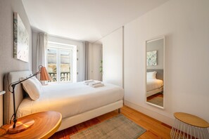 A modern bedroom with a bed, bedside table, lamp, and a view of the outside balcony. - GuestReady - Cosy stay near Money Museum (Lisbon)