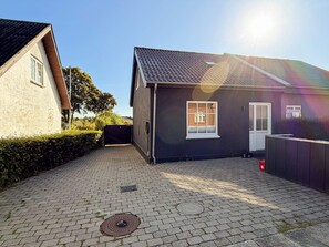 A residential property with a paved driveway, a black house with a white door, and a visible manhole cover. - 4 Star Holiday Home in Skanderborg (Skanderborg)