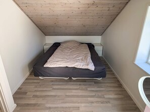 A small, narrow room with a bed, a nightstand, and a window. - 4 Star Holiday Home in Skanderborg (Skanderborg)