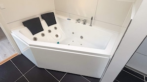 Uma casa de banho moderna com uma banheira branca, tapetes de banho pretos e chão em mosaico.