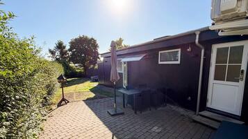 Een terras met een tafel, stoelen, een deur en een raam.