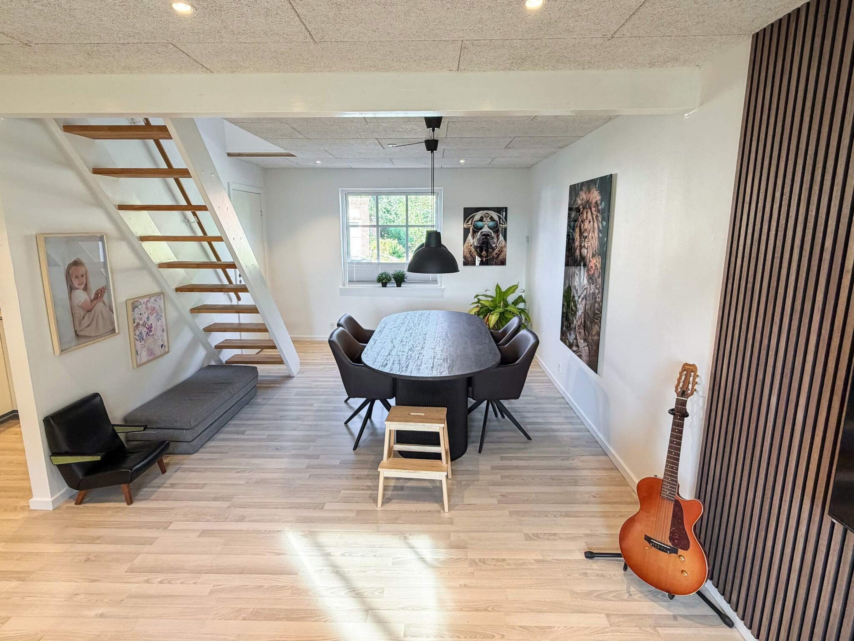 A modern interior with a dining area, a staircase, and a guitar.
