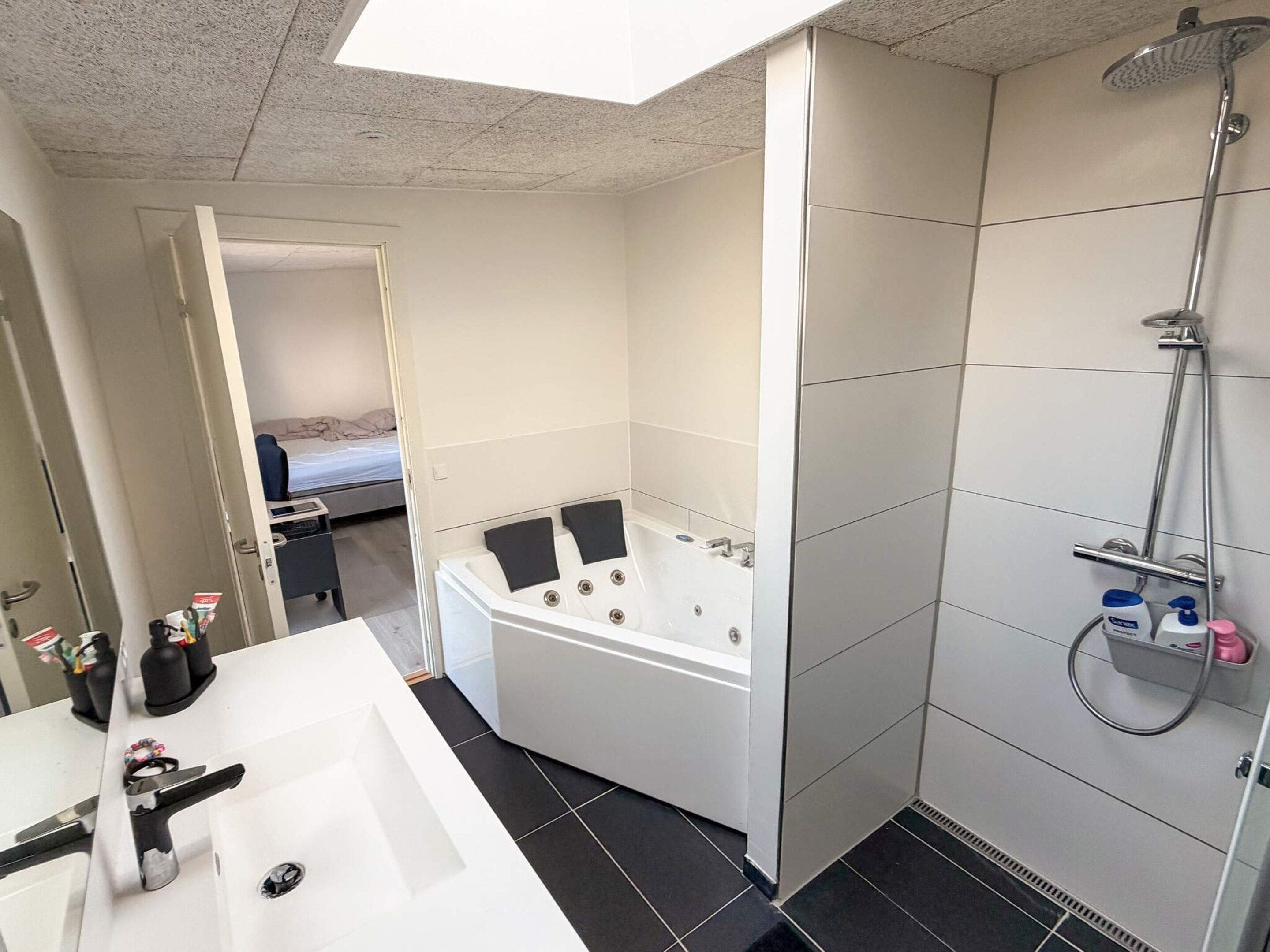Ein modernes Badezimmer mit einer großzügigen Badewanne, einer Duschkabine und einem separaten Waschbecken.