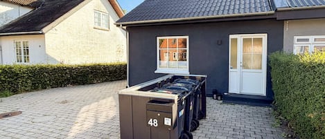 A residential building with a paved driveway, a mailbox marked with the number 48, and a door with a window.