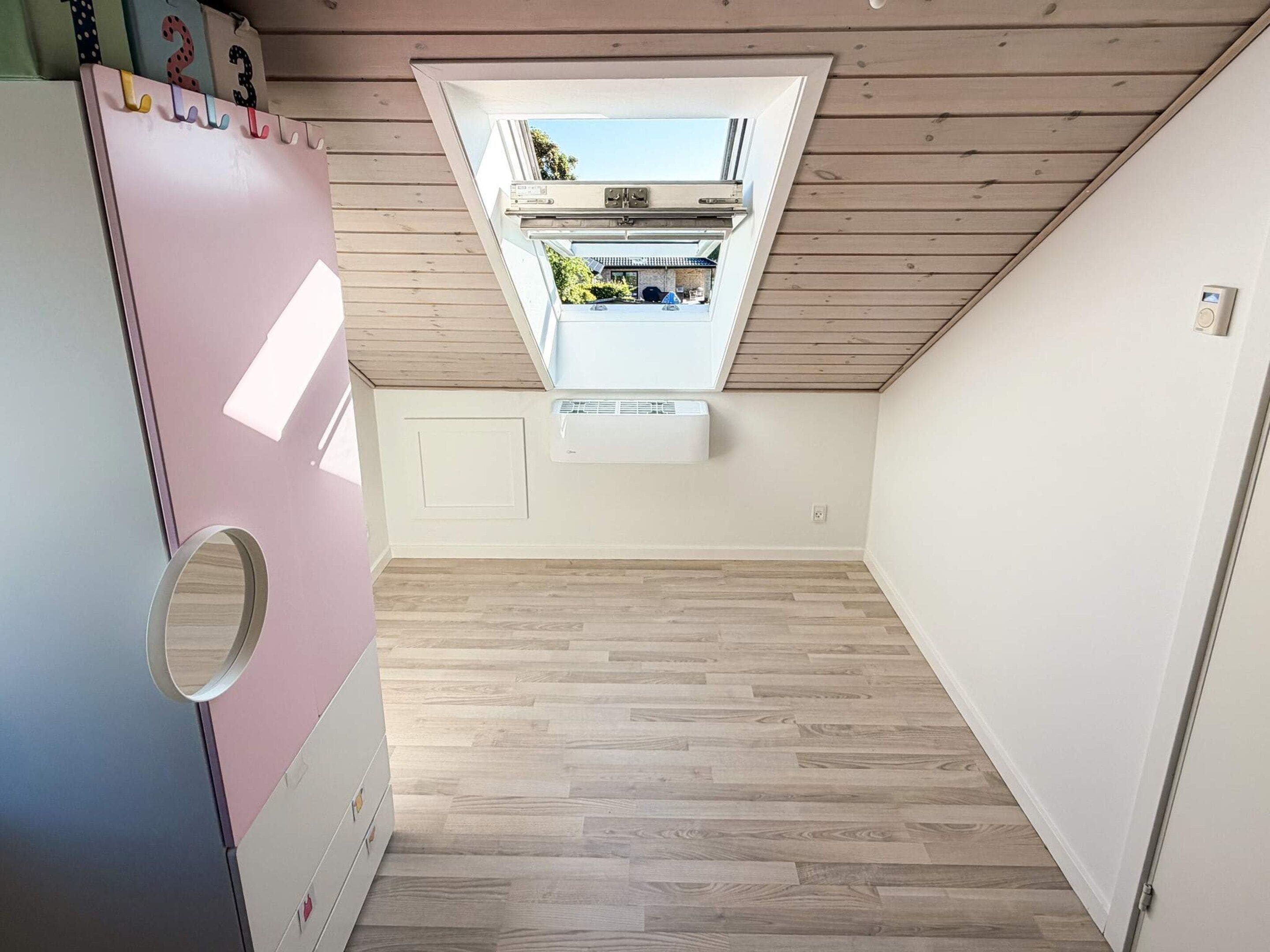 Une pièce dotée d’un plafond en pente, d’un système de climatisation intégré et offrant une vue sur le ciel grâce à une lucarne.