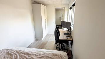 Un dormitorio con una cama, un escritorio con computadora y una silla.
