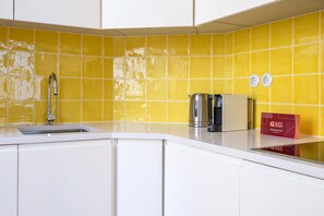 A kitchen with a yellow tiled backsplash, a stainless steel faucet, a kettle, a coffee maker, and a red 'Guest Ready' sign. - GuestReady - Striking apt near Santa Justa Lift (Lisbon)