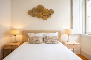 Une chambre à coucher comprenant un lit, deux tables de chevet, des lampes et un élément décoratif mural.