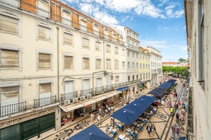 A street view with buildings, outdoor seating, and pedestrians. - GuestReady - Striking apt near Santa Justa Lift (Lisbon)