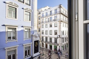 Une vue d’une rue bordée d’immeubles, avec une foule de personnes et un ciel dégagé.
