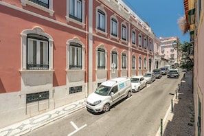 A street with parked cars and a building with arched windows and balconies. - GuestReady - Sleek home near the Botanical Garden (Lisbon)