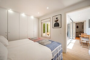 A bedroom with a bed, a window, and a view into the dining area. - GuestReady - Sleek home near the Botanical Garden (Lisbon)