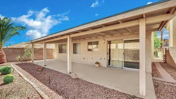 A covered patio area with a concrete floor, a brick wall, and a palm tree.