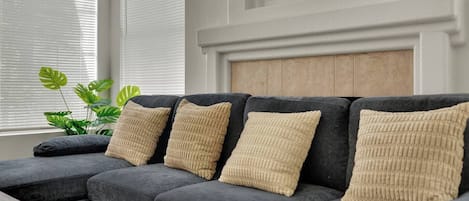 Un sofá modular con cojines color beige, ubicado en una habitación con pared blanca y cabecera de madera.