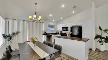 A modern kitchen with white cabinets, a black refrigerator, and a granite countertop.