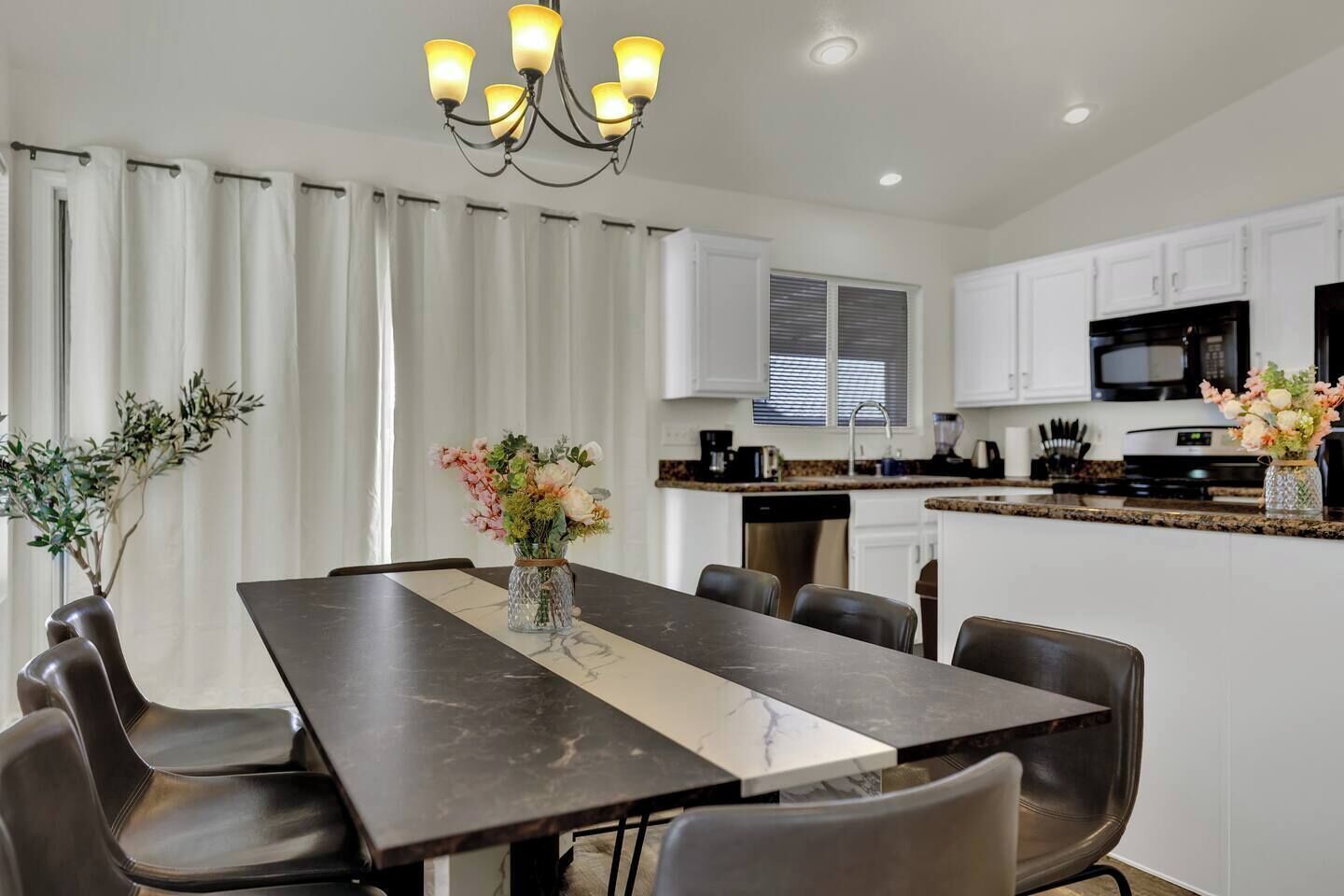 A modern kitchen with white cabinets, a black microwave, and a granite countertop.