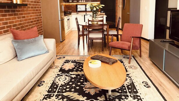 A modern living room with a sofa, a coffee table, and a red armchair. - Undiscovered Gem in Rosebank 2BR (Johannesburg)