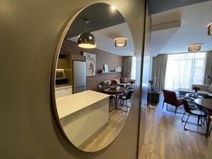 A modern kitchen with a central island, a dining area with a round table, and a living space with a sofa and a TV.