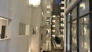 A modern building with a central atrium, multiple floors, and a view of the surrounding area. - Undiscovered Gem in Rosebank 2BR (Johannesburg)