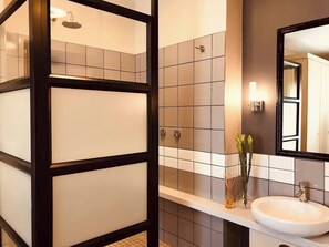A modern bathroom with a white sink, a mirror, and a shower enclosure.