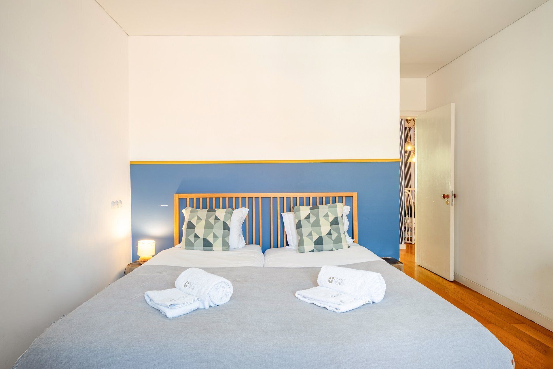 Ein Hotelzimmer mit einem Bett, zwei Handtüchern, einem Kopfteil und einem Nachttisch mit einer Lampe.