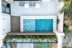 A modern outdoor pool area with a tiled wall, two round tables, and a seating bench. - Studio W/balcony Near the Beach One0302 (Salvador)