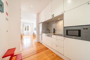 A modern kitchen with white cabinetry, a microwave, and a sink. - GuestReady - Trendy stay with sea view in Lapa (Lisbon)