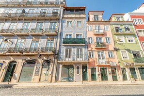 A row of colorful buildings with balconies, some with plants, and a cobblestone street. - GuestReady - Trendy stay with sea view in Lapa (Lisbon)