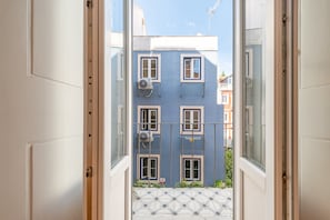 A view through an open door of a building with multiple windows and balconies, leading to a tiled courtyard. - GuestReady - Trendy stay with sea view in Lapa (Lisbon)