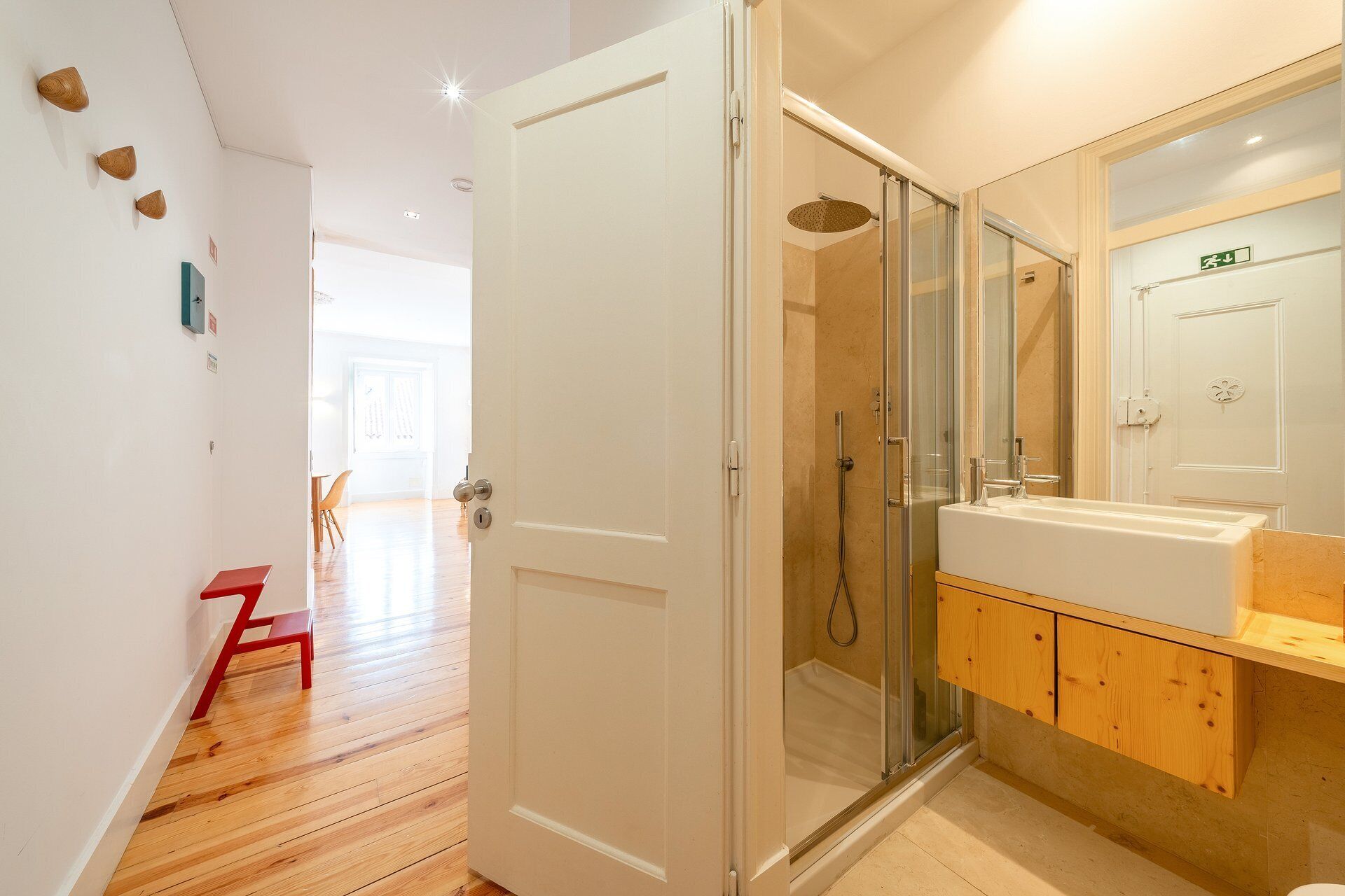 A modern bathroom with a glass shower enclosure, a white sink, and wooden cabinets.