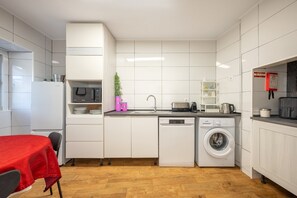 Eine kleine Küche mit weißen Schränken, einem integrierten Geschirrspüler, einer Waschmaschine und einer Mikrowelle.