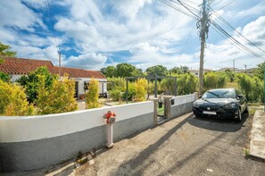 Eine Wohnstraße mit einem parkenden Auto, einem Hydranten und einem weißen Gebäude mit roten Ziegeldach.